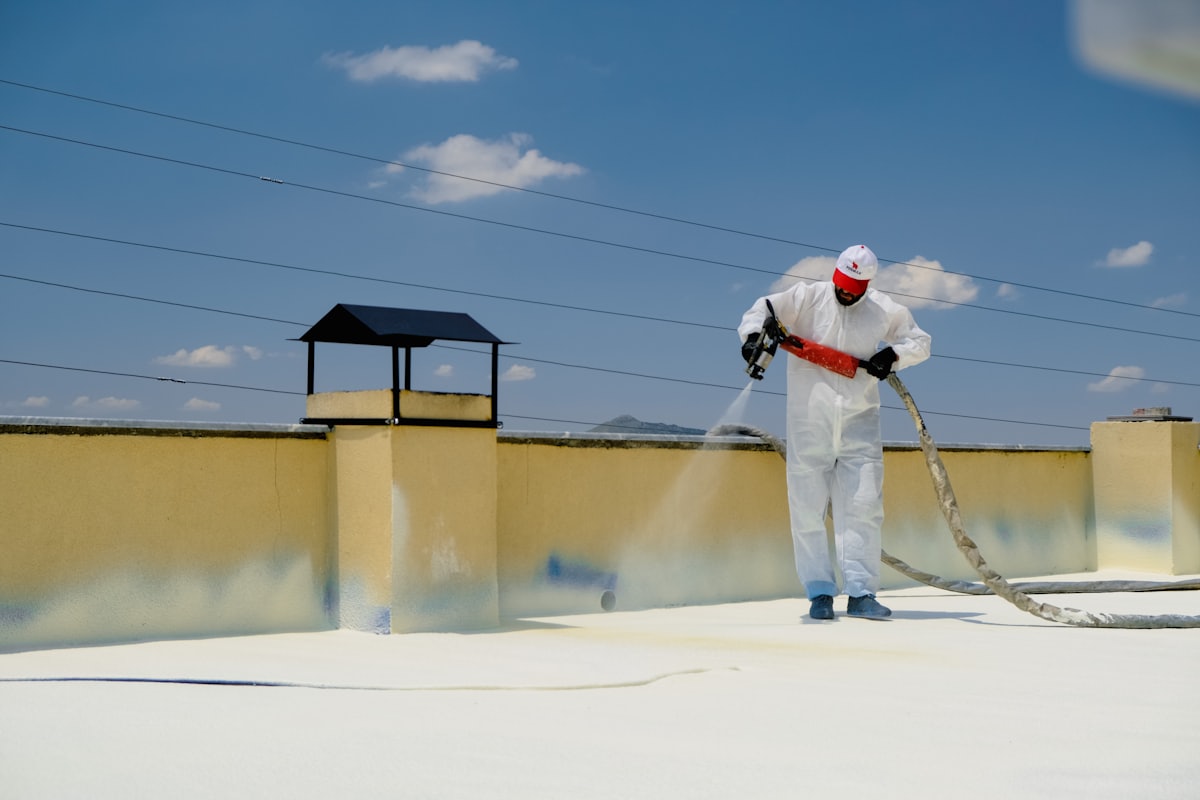 White silicone roof coating being applied to a flat commercial roof